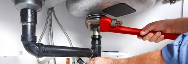 Garbage disposal repair technician tightening the sink drain and disposal connection in Pasadena, CA