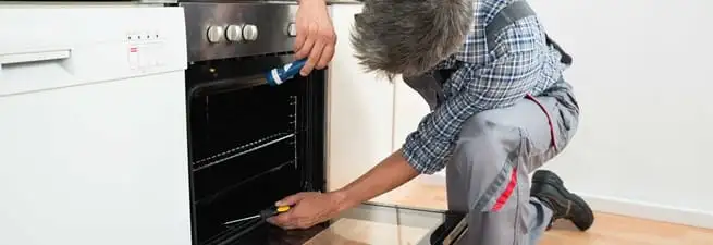 Oven repair technician inspecting and servicing an electric oven in Pasadena, CA