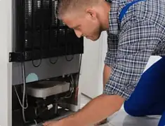 Refrigerator repair technician servicing the compressor and condenser area in Pasadena, CA