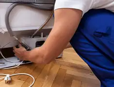 Appliance repair technician fixing refrigerator water line and connections in Pasadena, CA
