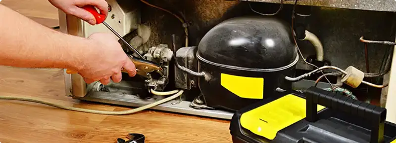 Refrigerator repair technician fixing the compressor and wiring in Pasadena, CA